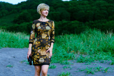 Full length of young woman standing against plants