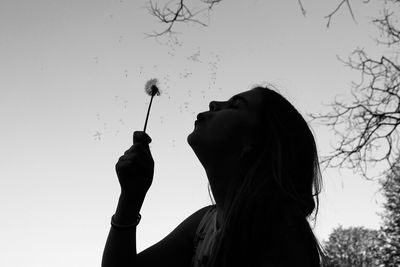 Silhouette of girl holding a dandelion flower