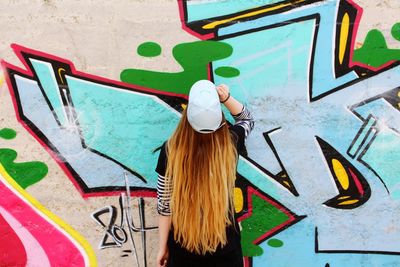 Woman standing by graffiti on wall