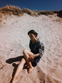 High angle view of woman sitting on sand at beach