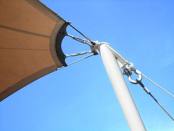 Low angle view of telephone pole against clear blue sky