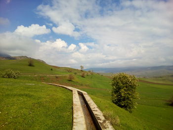 Road amidst green landscape against sky