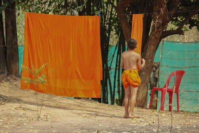 Rear view of shirtless man standing against wall