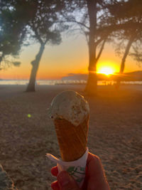 Person holding ice cream cone on land during sunset