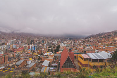 High angle shot of cityscape against cloudy sky