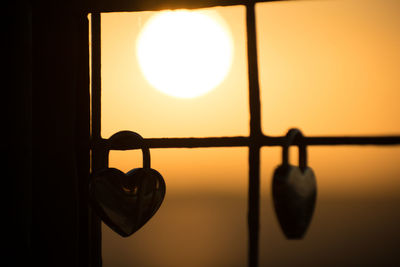 Close-up of silhouette hanging light against window