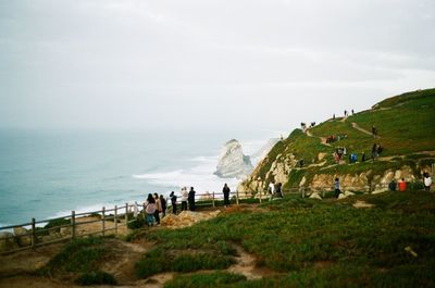 High angle view of people standing by railing against sea and sky