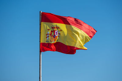 Low angle view of flag against clear blue sky