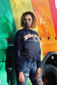 Portrait of smiling young woman standing by car