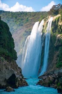 Scenic view of waterfall by sea against sky