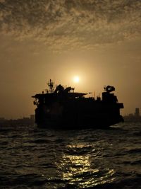 Silhouette boat in sea against sky during sunset