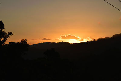 Scenic view of silhouette mountains against orange sky