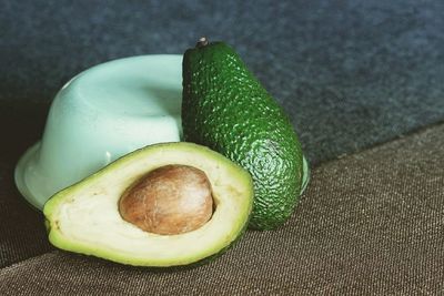 Close-up of avocado slices with bowl on tablecloth