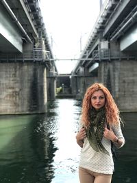 Portrait of beautiful woman standing on bridge over canal