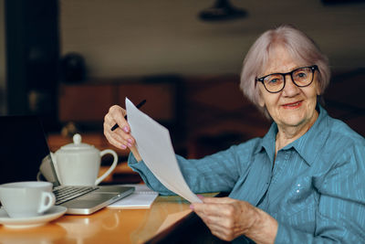 Portrait of senior woman holding document in cafe