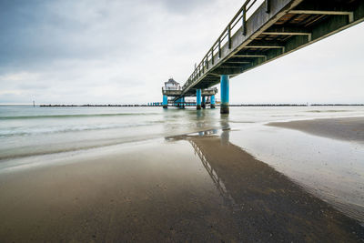 View of suspension bridge over sea against cloudy sky