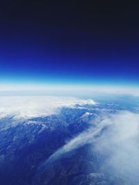 Aerial view of snowcapped landscape against blue sky