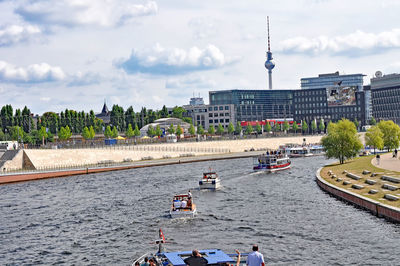 Boats on river in city against sky