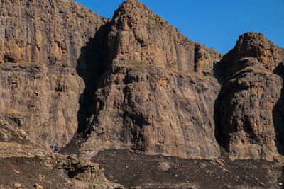 Two men standing looking ahead of the path while hiking next to big mountains 