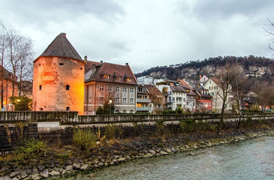 Buildings by river against sky