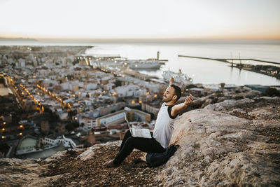Young man relaxing in city against sky