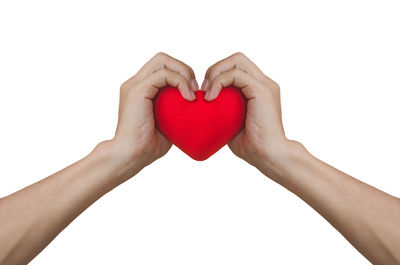 Close-up of woman hand holding heart shape against white background