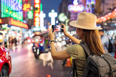 Midsection of woman photographing on city street