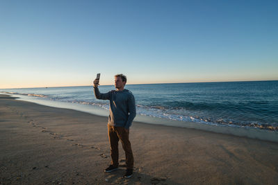 Full length of man running on beach against clear sky