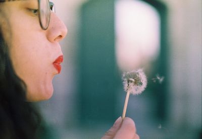 Close-up of woman holding dandelion flower