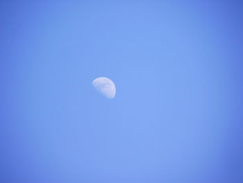 Low angle view of moon against blue sky