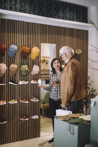 Smiling saleswoman showing shoes to senior male customer in fashion boutique