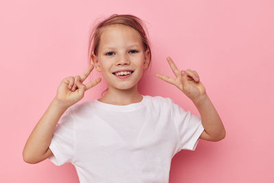 Portrait of girl gesturing against pink background