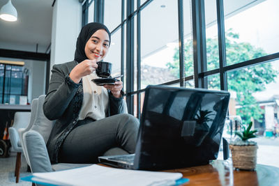 Young woman using mobile phone while sitting in cafe