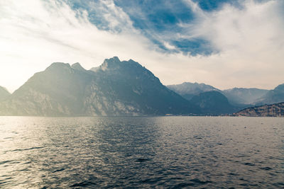 Scenic view of sea by mountains against sky