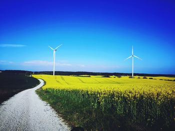 Wind turbines on field against sky