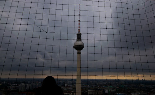 Der berliner fernsehturm hinter einem gitter. der hintergrund ist dunkel.