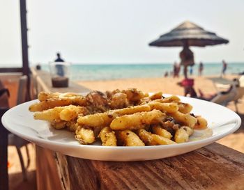 Close-up of food served on table at beach against sky
