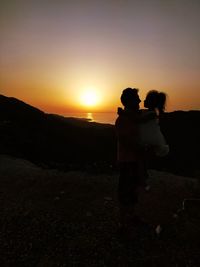 Couple standing on land against sky during sunset