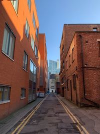 Empty road amidst buildings against sky