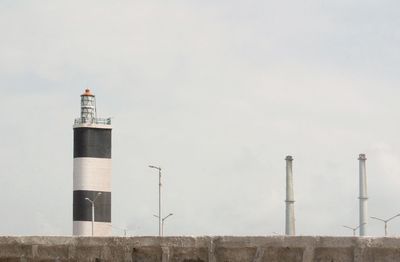 Lighthouse in factory against sky