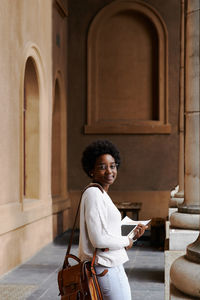 Woman holding papers while standing outdoors