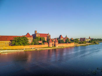 Buildings at waterfront against blue sky