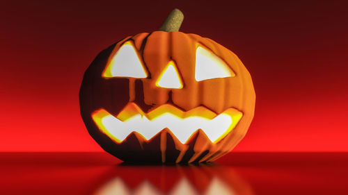Close-up of illuminated pumpkin against red background