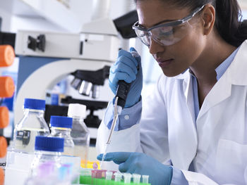 Genetic research, female scientist pipetting dna or chemical sample into a eppendorf vial, analysis in the laboratory