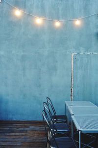 Grey wall, three chairs and some lamps