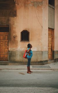 Full length of woman standing on street against building