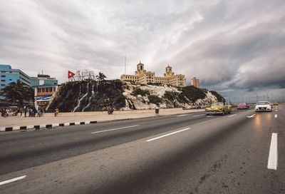 View of city street against cloudy sky