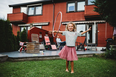 Cute girl in tutu playing with hula hoop in her backyard in norway