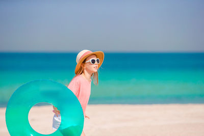 Woman wearing sunglasses on beach against sky