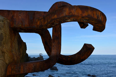 Rusty metallic structure on sea against sky